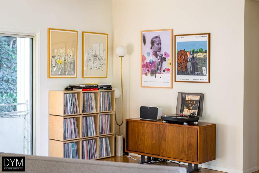 A corner of a room in a modern home with cube shelving, art, and a record player.